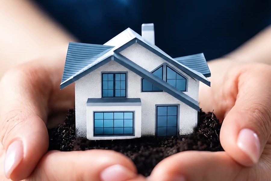 A pair of hands holding a small model house