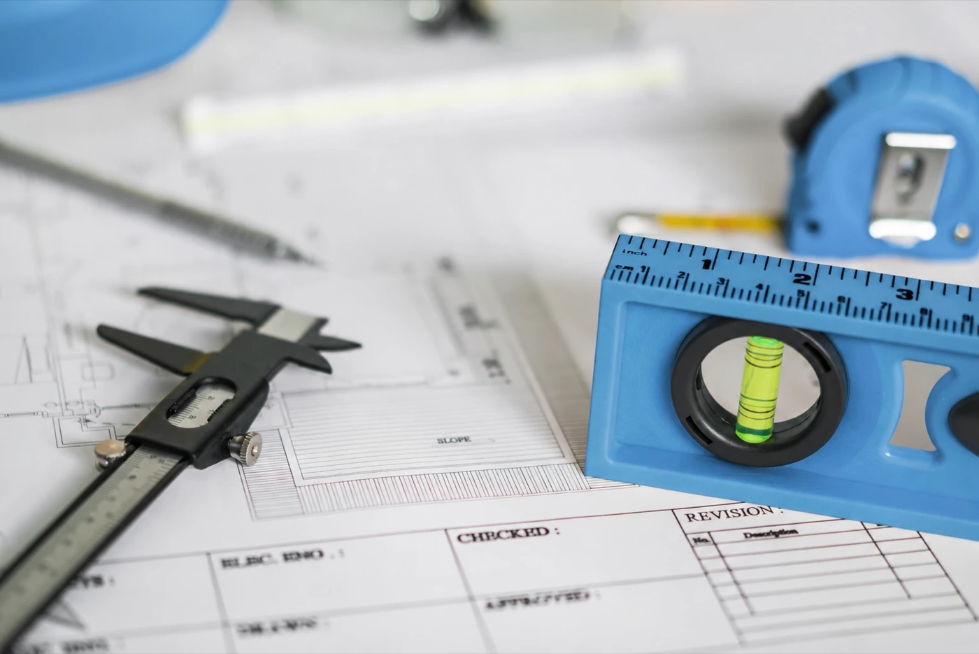 A spirit level, callipers and tape measure on a set of building plans